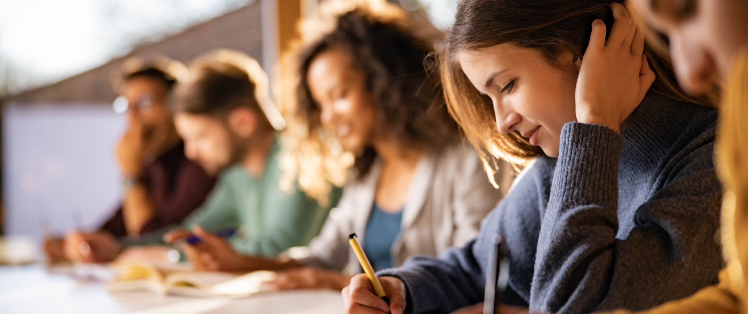 Smiling college student writing during a class at the university.